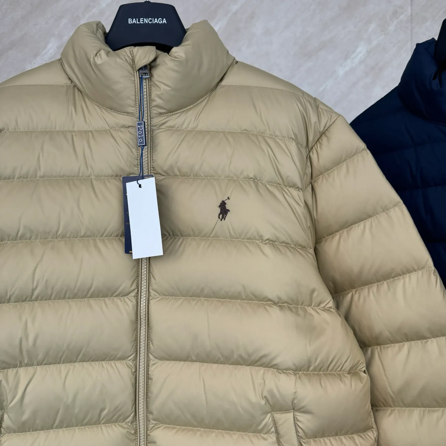 P930 Ralph Lauren lightweight down jacket size s m l xl The nylon fabric has good windproof and waterproof properties, which can effectively block the intrusion of wind and rain from the outside and keep the inside dry, suitable for wearing in humid or rainy environments.  The red label on the chest is made with an imported MECLO embroidery machine. The original pattern is scanned first, and then high-quality silk thread is used to make a pattern. The density effect is adjusted by continuous pattern making.  Exquisite details: the zipper design is simple and elegant, easy to operate; the closing design of the cuffs and hem effectively prevents the intrusion of cold wind, improving the warmth and comfort of wearing.  High-quality filling: 90 white duck down is selected, with a weight of 260g, ensuring excellent thermal insulation performance. After strict screening and processing, the velvet is not easy to drill, ensuring durability. The hangtags, wash marks, air holes, and four-button buttons are all customized from the original one-to-one mold.